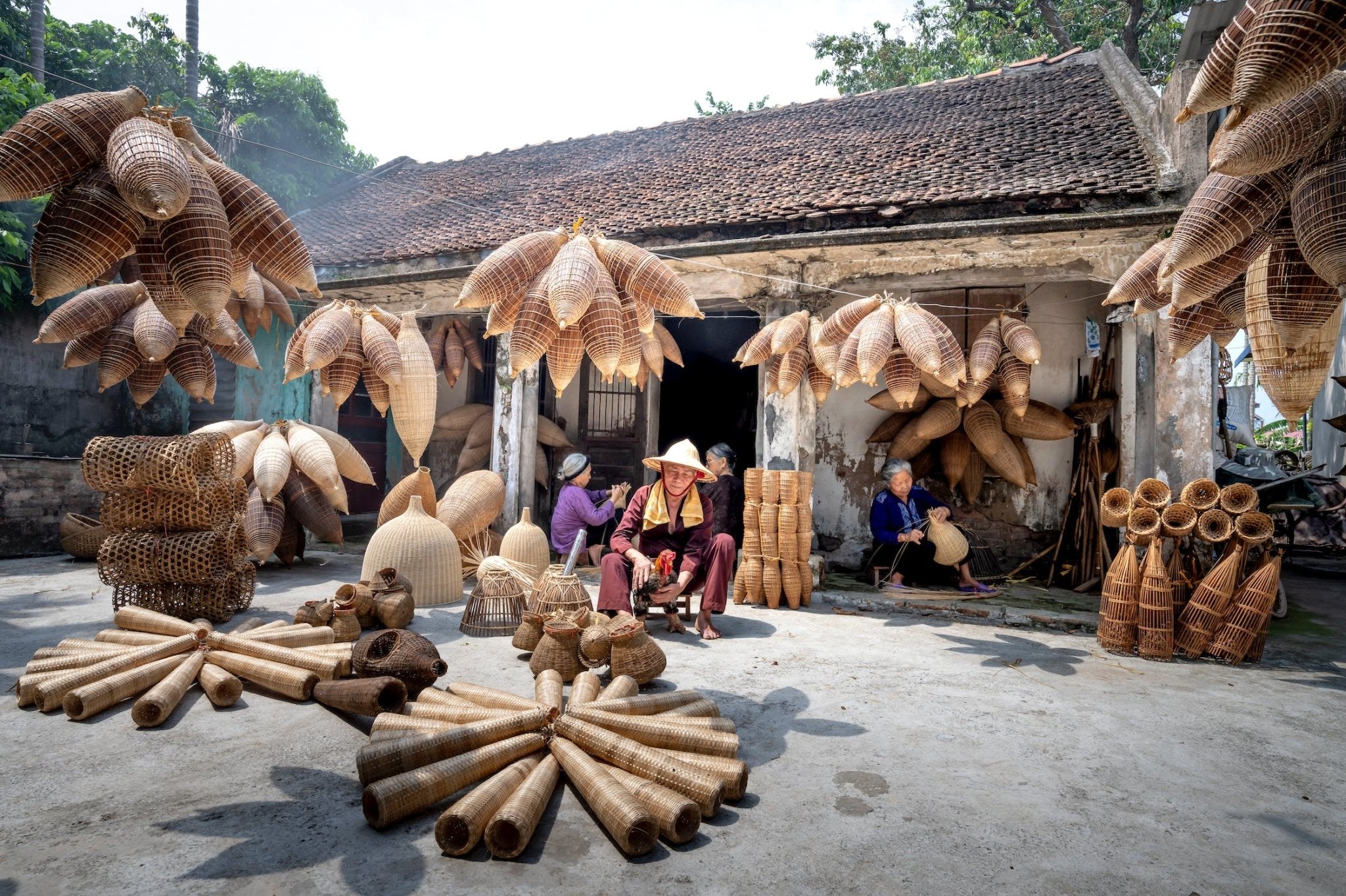 baskets and woven crafts displayed outside a workshop in a rural setting with artisans working