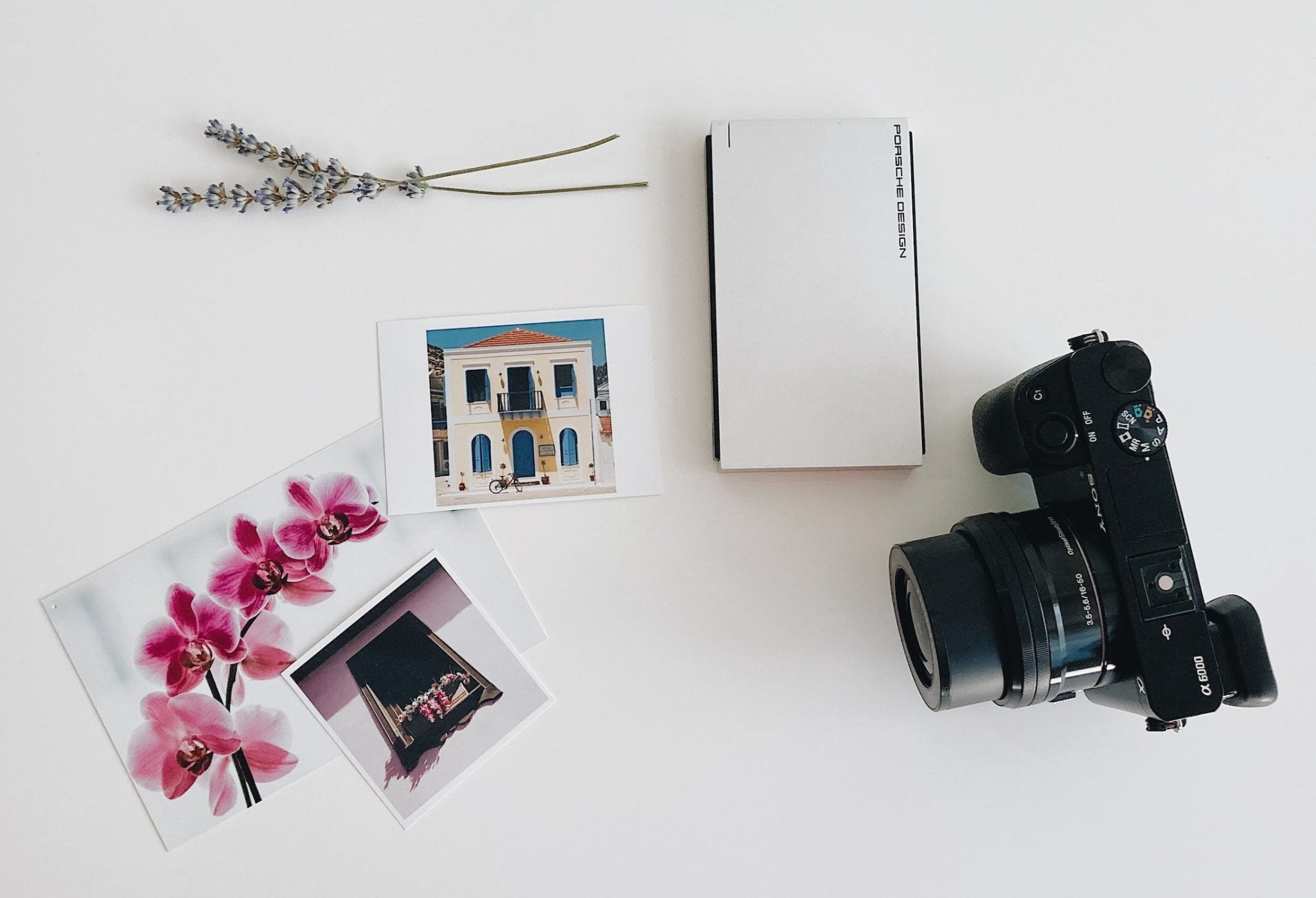 Camera with lens, photographs of flowers and buildings, lavender sprigs, and a white box.