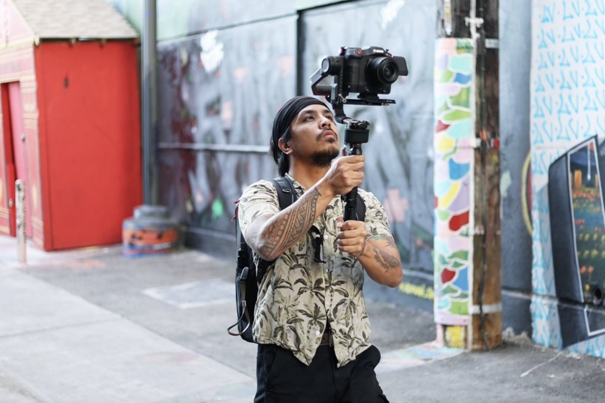 person holding a Canon camera on a gimbal in an urban setting