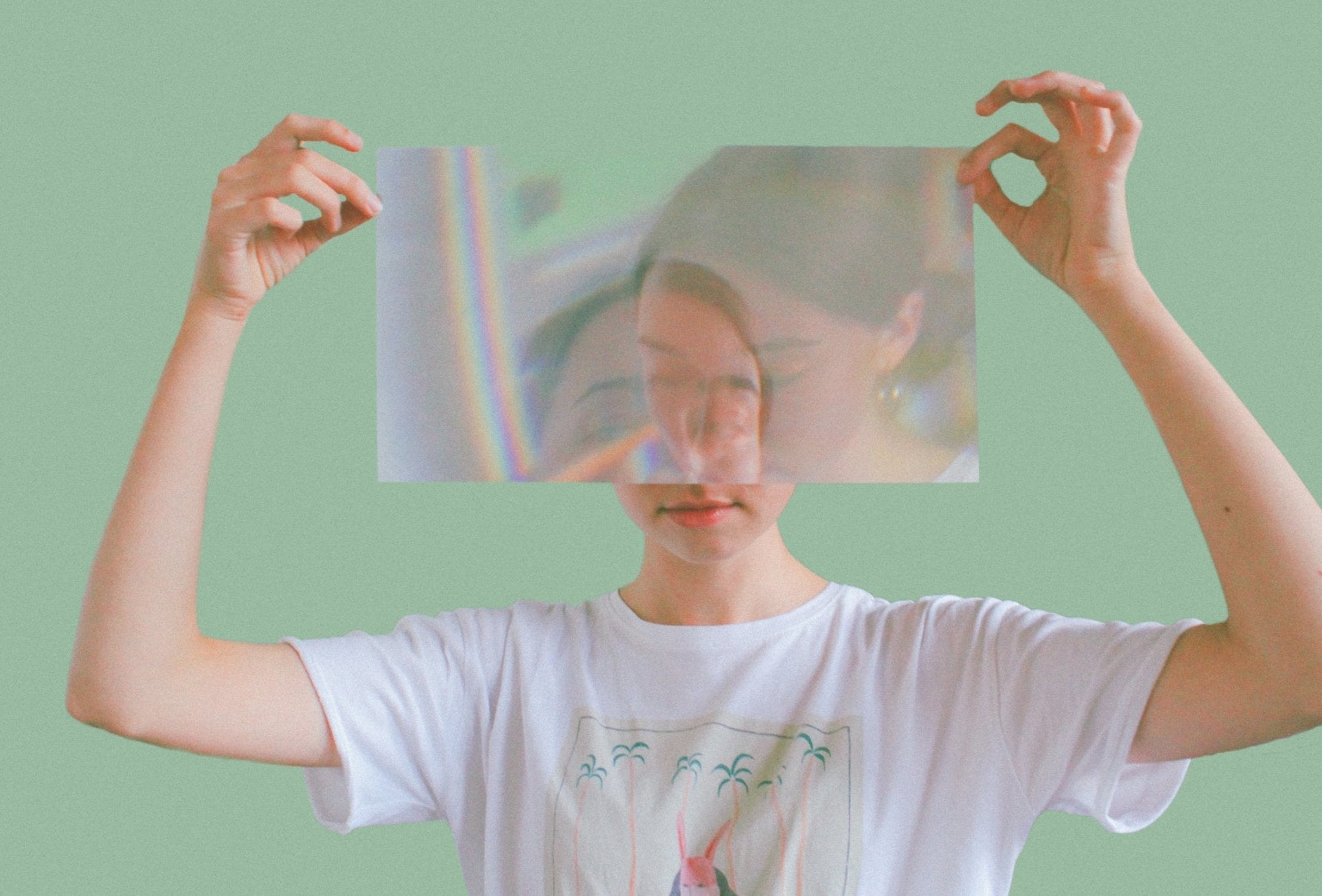 Woman holding a transparent sheet with a distorted image in front of her face.