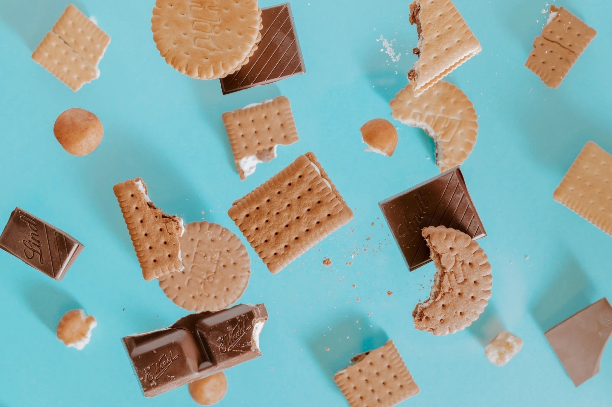 assorted cookies and chocolate pieces scattered on a bright blue background