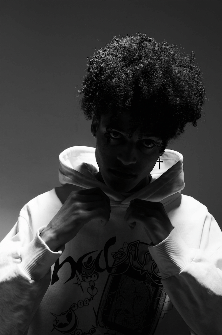 Black and white portrait of a person in a hoodie, with dramatic low-key lighting and intense expression.