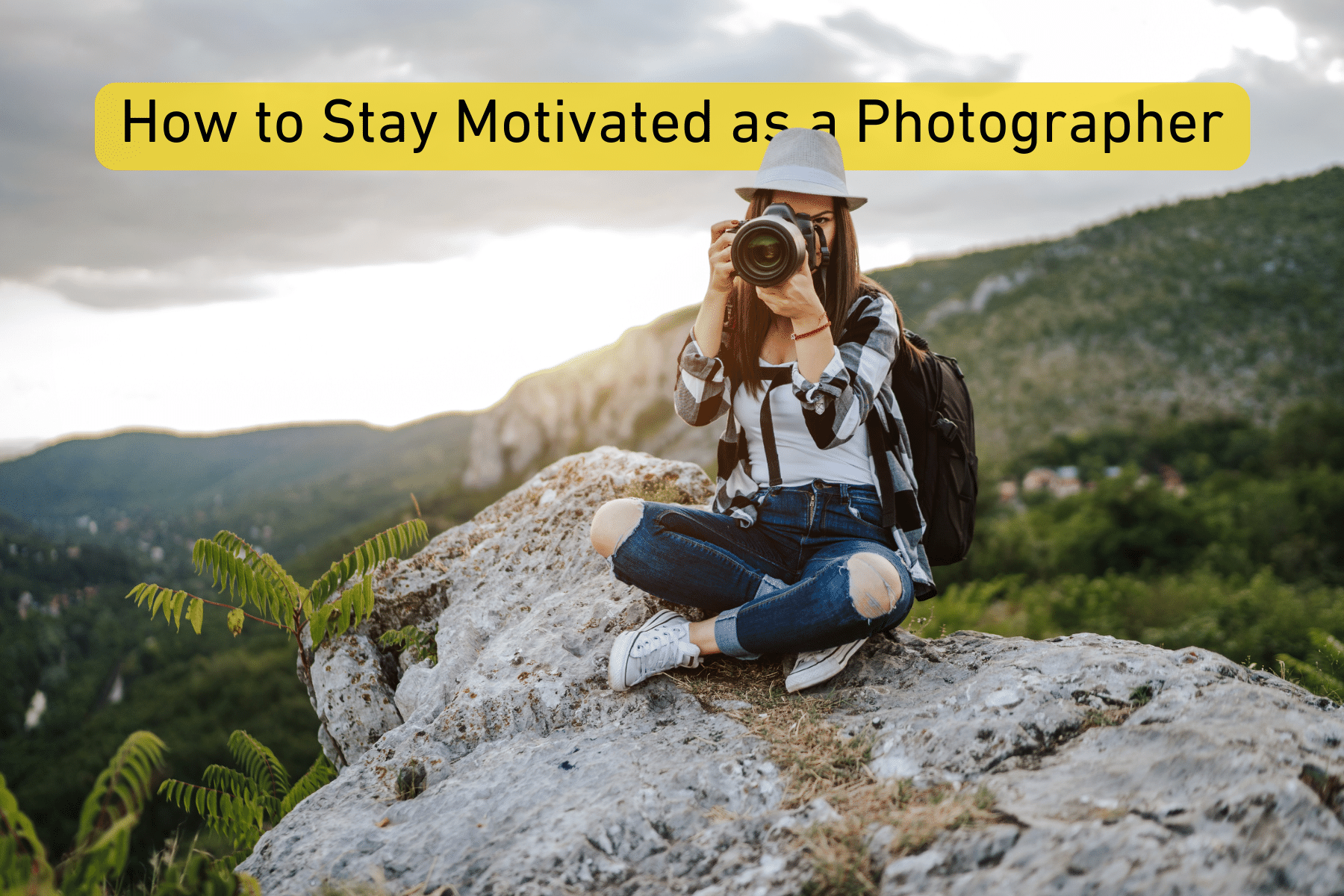 Woman sitting on a rock with a camera, wearing a hat and backpack, surrounded by a landscape.