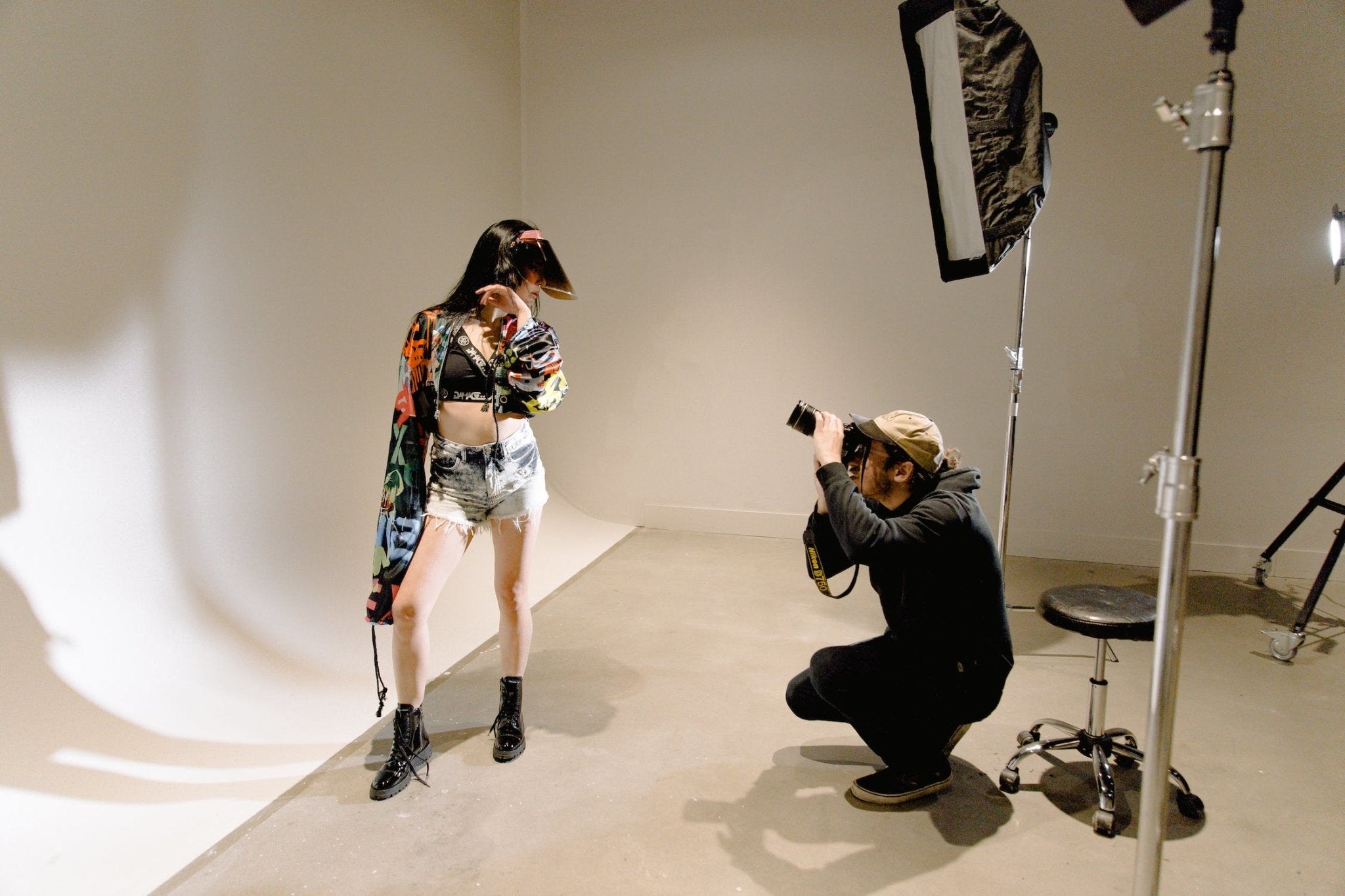 A photographer capturing a model wearing a colorful outfit in a studio with lighting equipment.
