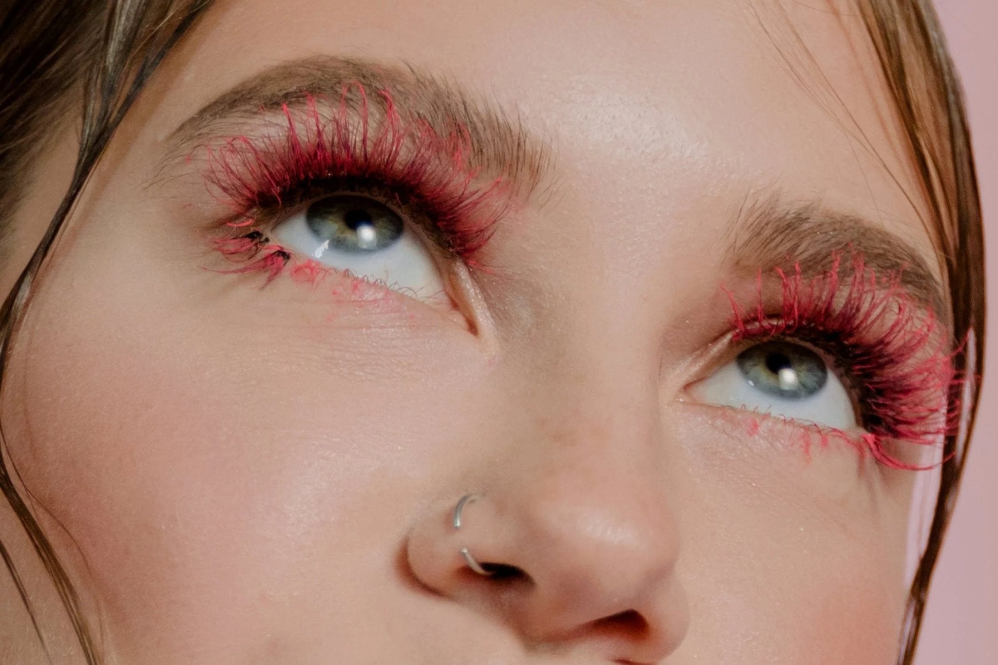Close-up of eyes with bright red eyelashes and a natural makeup look.