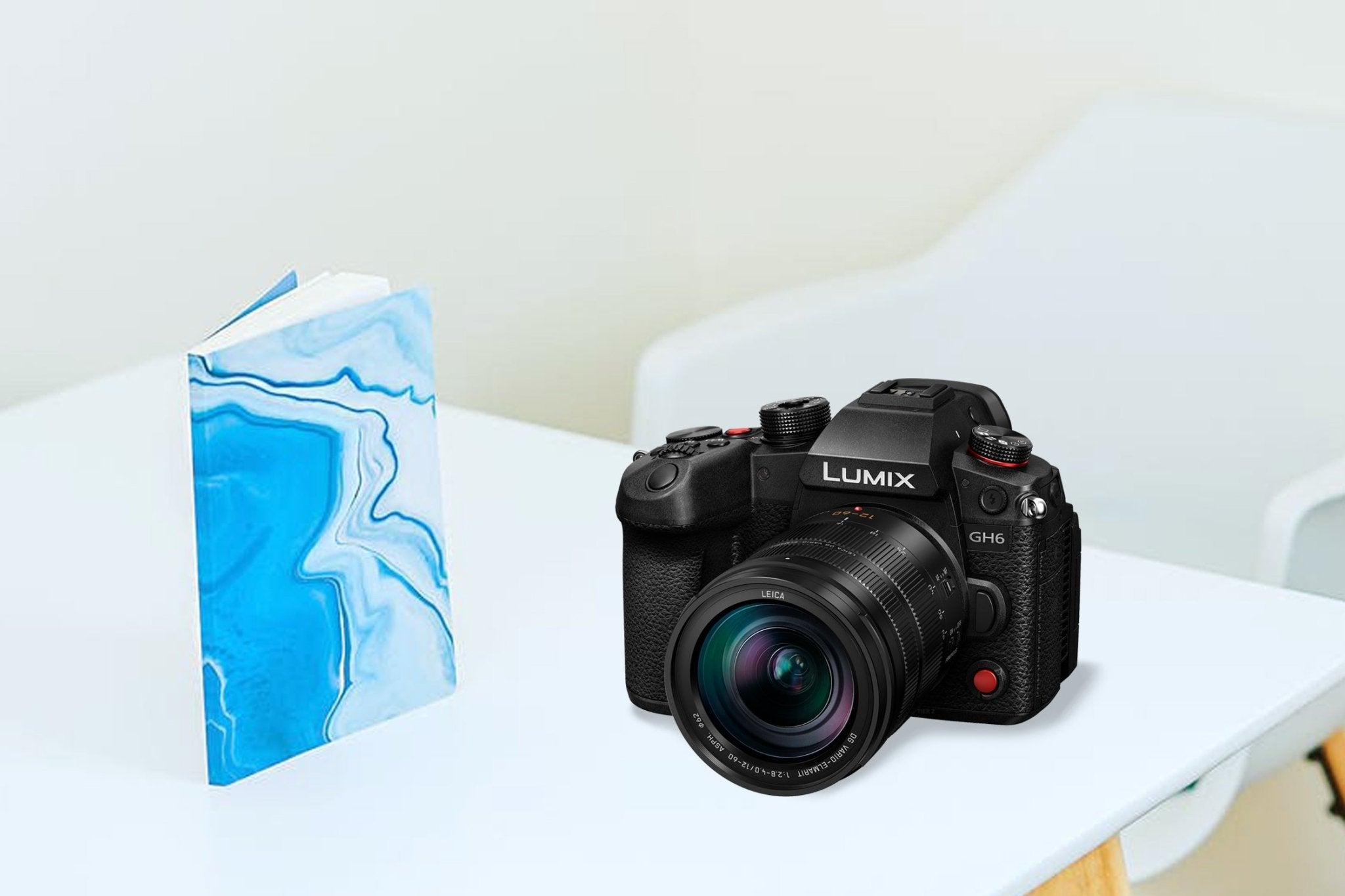 Black Panasonic Lumix GH6 mirrorless camera on a table next to a blue marbled notebook.