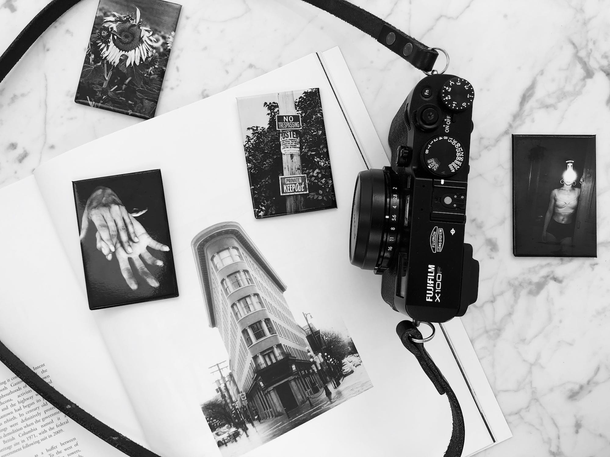 Black and white photo of a camera on an open book with various photos scattered around.