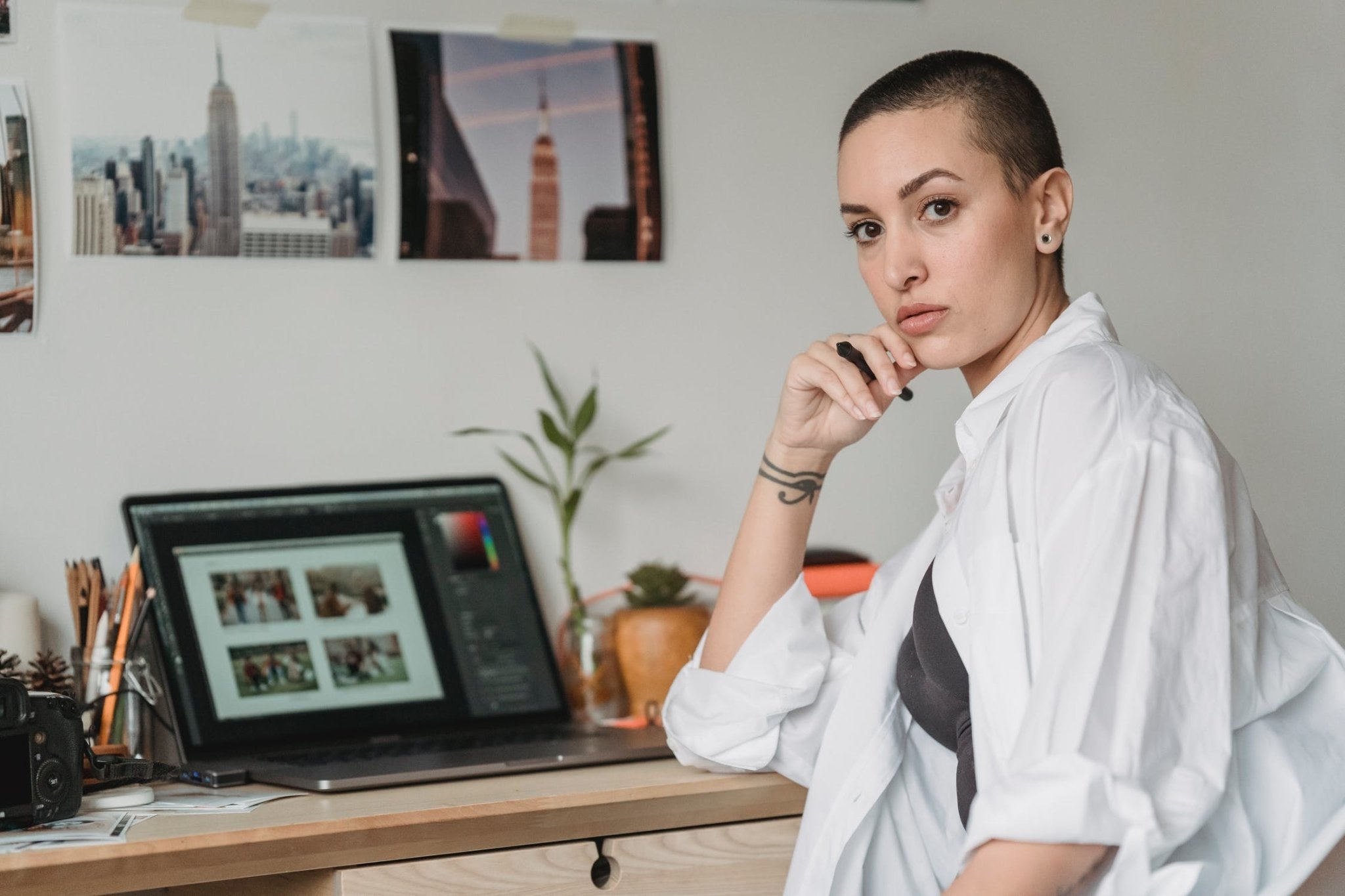 female photographer sitting at a desk with a computer and photographs on the wall