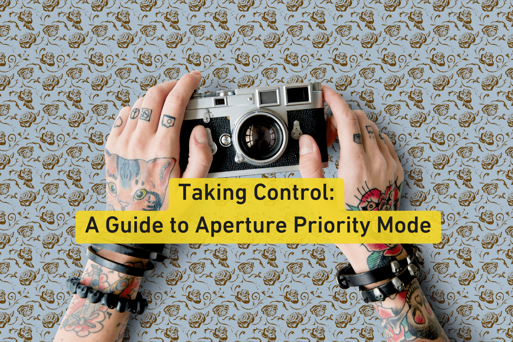 Hands with tattoos holding a vintage camera on a patterned background.