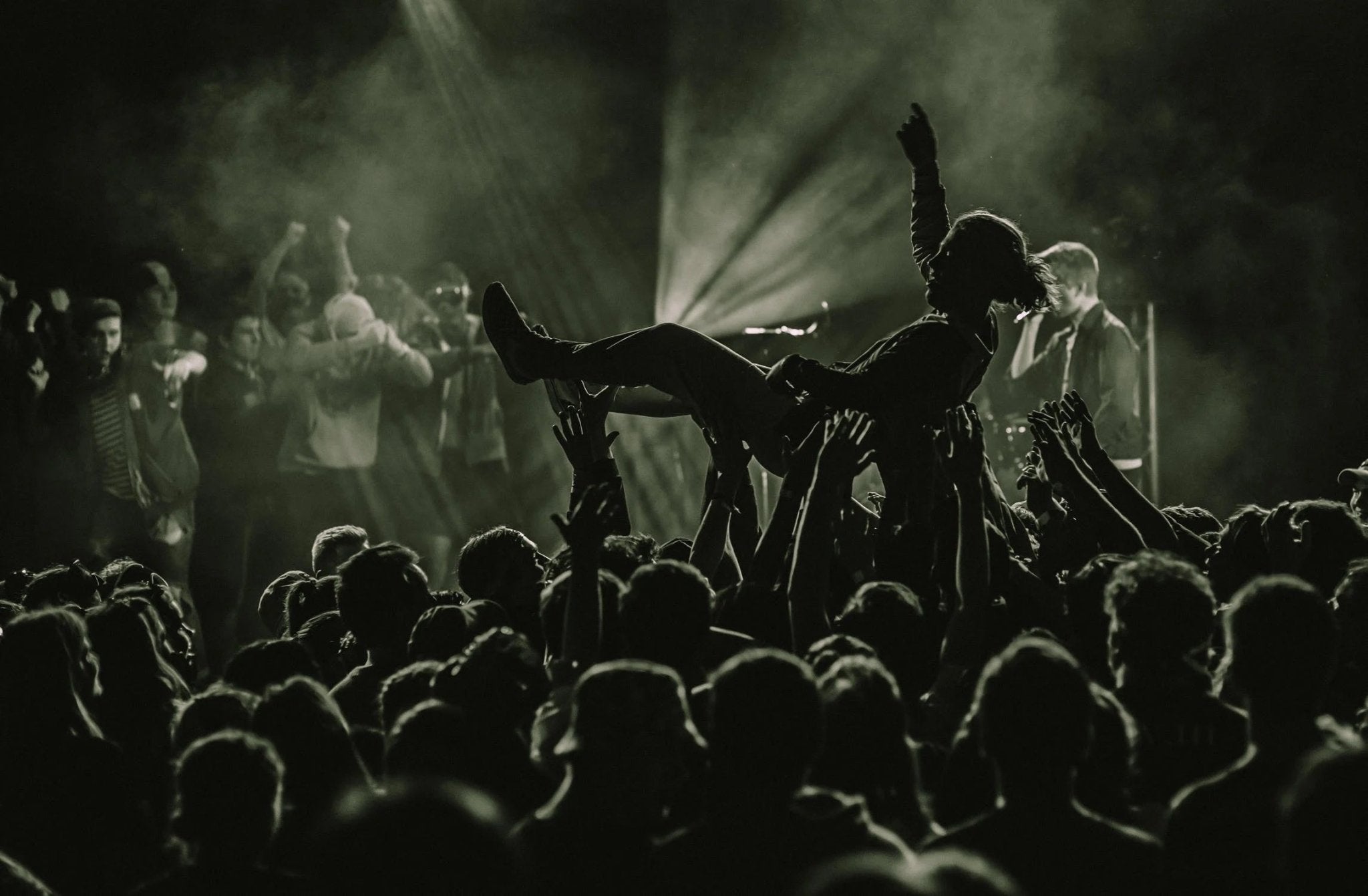 Black and white crowd at a nightclub concert, with a person crowd surfing.