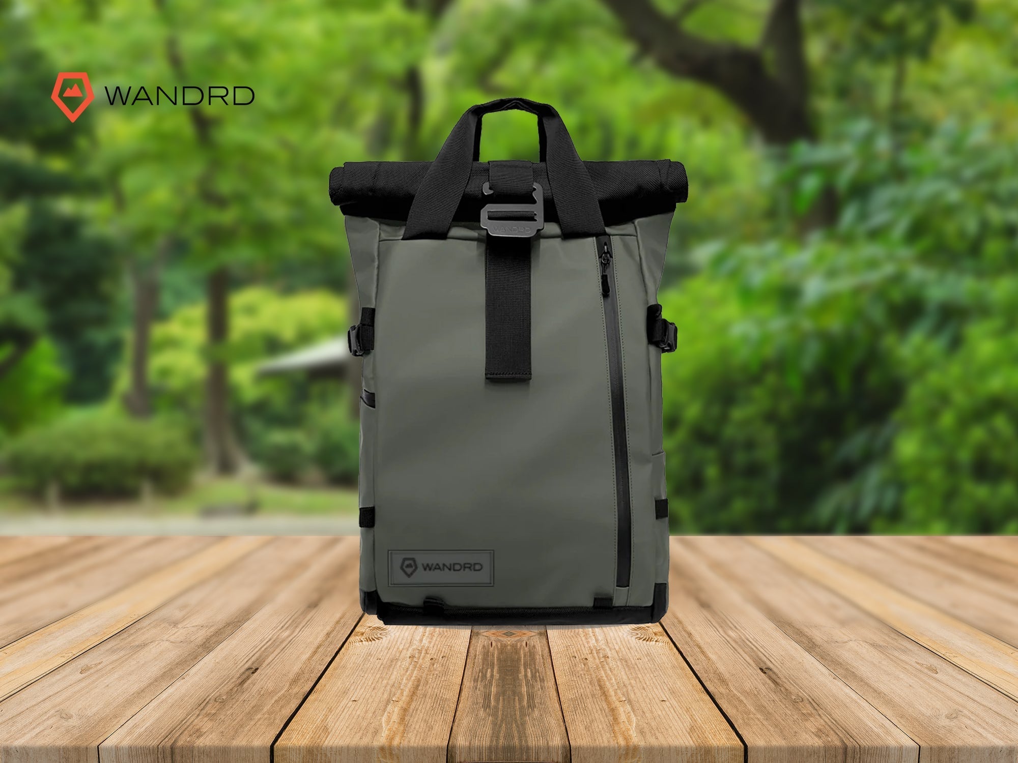 Gray Wandrd photography bag on a wooden table with a green outdoor background.