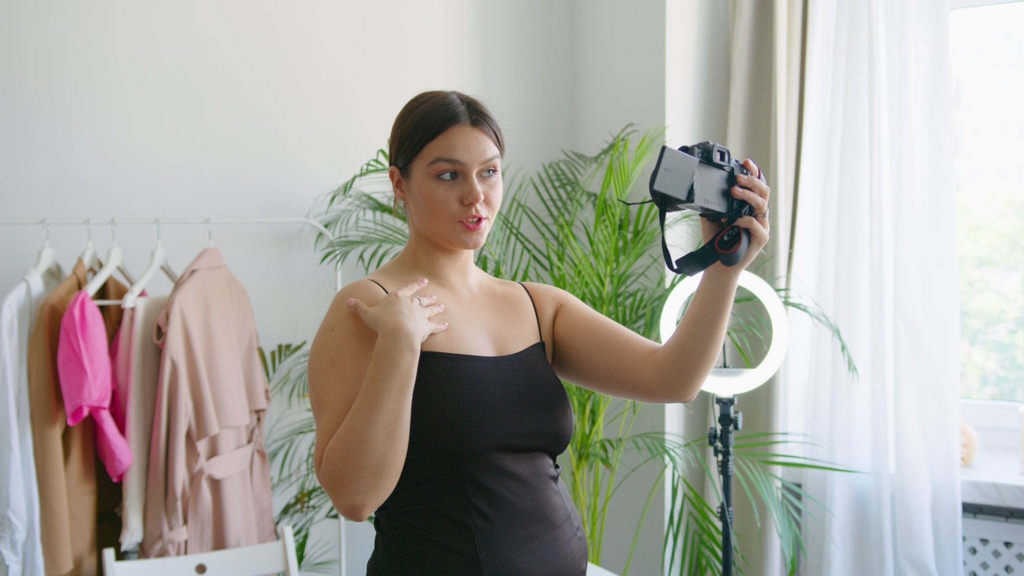 Young woman vlogging with a camera in a well-lit room.
